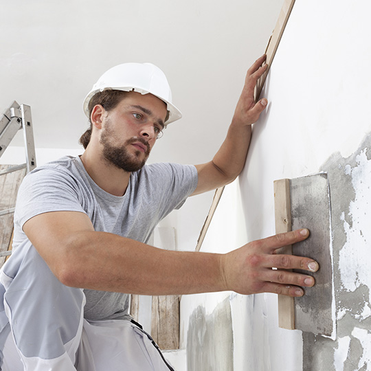 Handwerker verputzt Wand in einem Haus.
